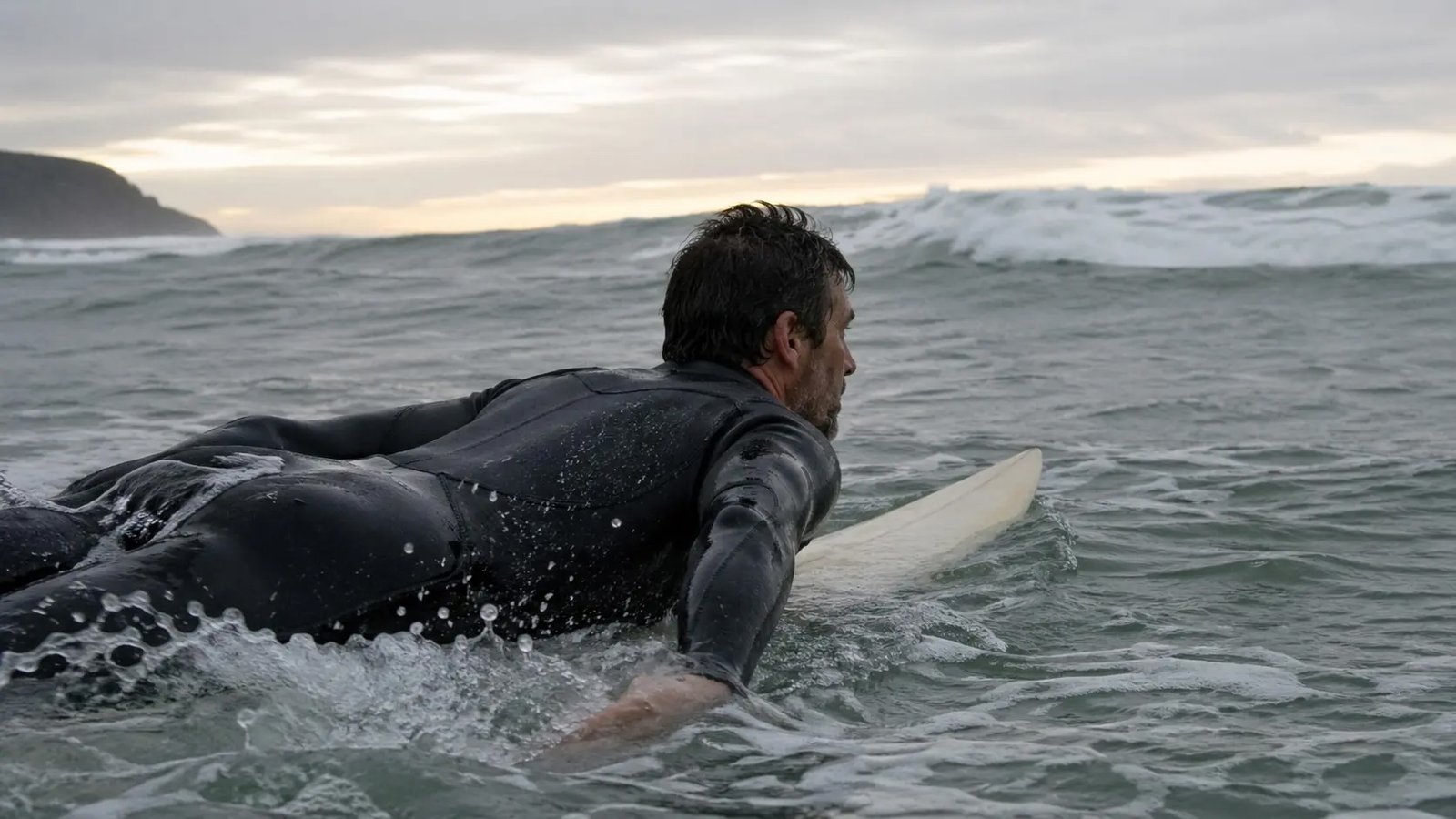 Surfista adulto paddleando en prone sobre su tabla en el mar Cantábrico